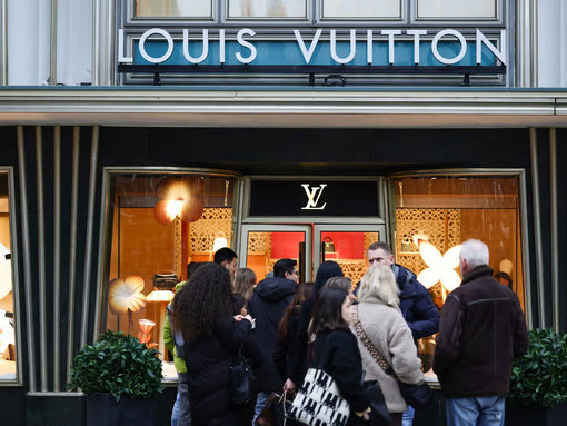 Vetrina Louis Vuitton con insegna del marchio e passanti davanti al negozio